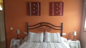 Cama de casal com roupa de cama listrada, duas almofadas, duas mesas de cabeceira com abajures e dois interruptores de luz na parede.