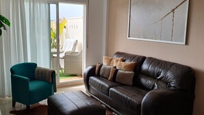 Un salon avec un canapé en cuir, un fauteuil turquoise et un tapis en peau de vache.