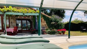 A poolside area with lounge chairs, a covered patio, and a stone building with a door and windows. - La Blatière Farmhouse-pool, sauna&gym-games room.Rural setting close to it all.  (La Chapelle- Saint-Etienne)
