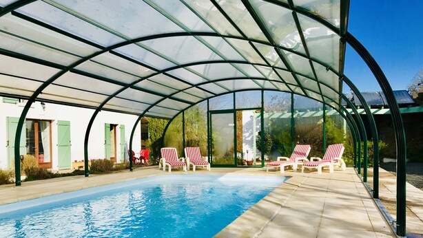 A covered swimming pool with lounge chairs and a glass enclosure. - La Blatière Farmhouse-pool, sauna&gym-games room.Rural setting close to it all.  (La Chapelle- Saint-Etienne)