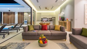 A modern living room with a sofa, a dining table, and a fruit bowl. - Baan Ouyan 5-bed luxury family home on Bophut Hill (Ko Samui)