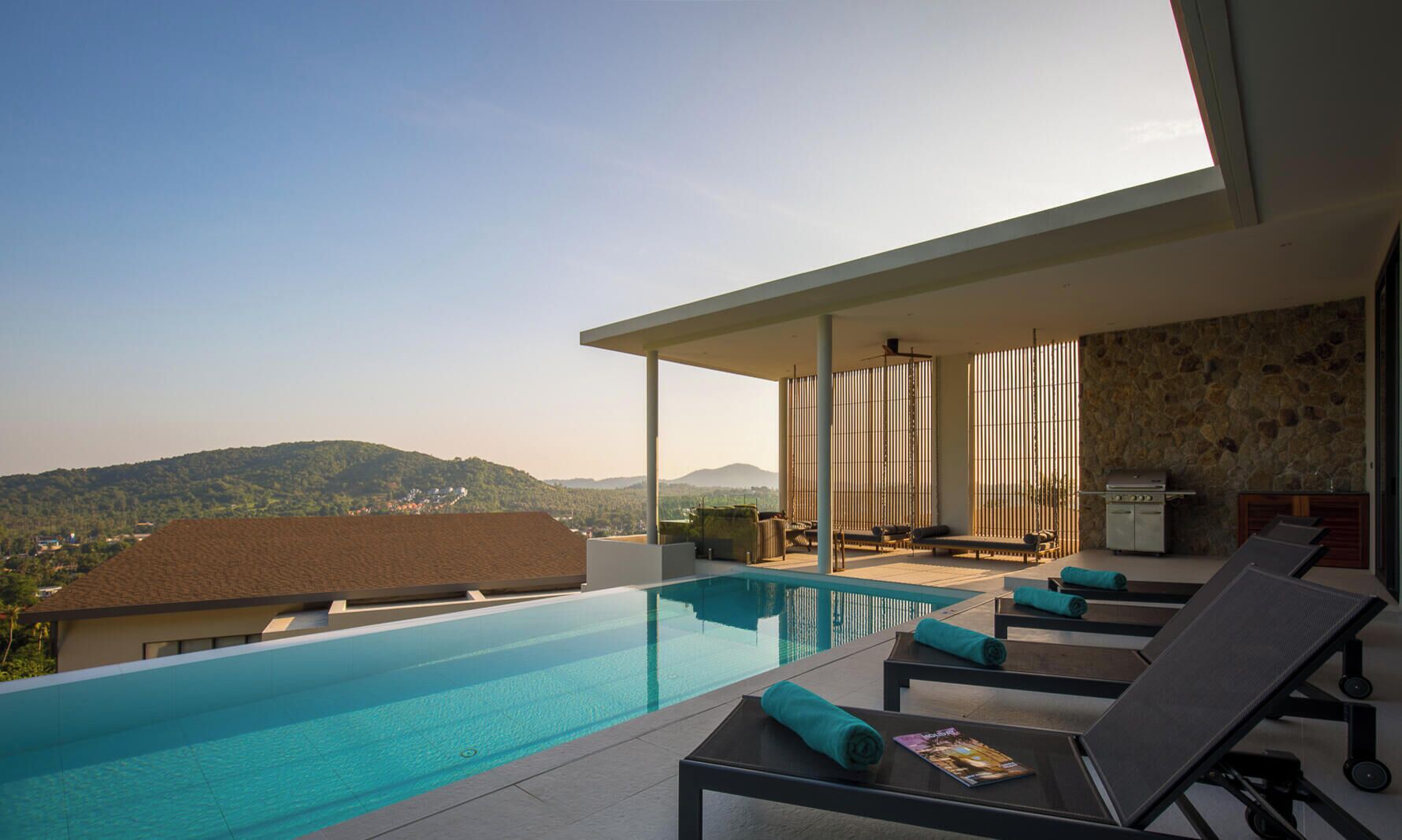 A modern infinity pool with lounge chairs and a stone wall backdrop.