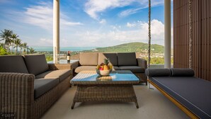 A balcony with wicker furniture, a glass-top table, and a bowl of fruit. - Baan Ouyan 5-bed luxury family home on Bophut Hill (Ko Samui)