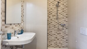 Une salle de bain avec un lavabo blanc, un miroir et une douche aux carreaux de mosaïque.