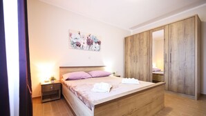 A bedroom with a wooden bed, a nightstand, a bedside table, a wardrobe, and a floral painting on the wall. - Villa Levatinka ZadarVillas (Prkos)