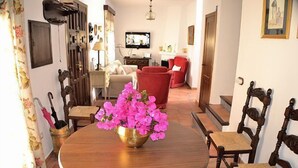 Ein Essbereich mit einem runden Holztisch, einer Messing-Schale mit rosa Blumen und Holzkästen.