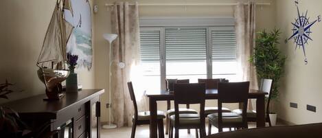 A dining area with a table and chairs, a ship model, and a compass wall decoration.