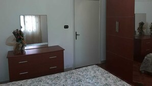 Une chambre à coucher comprenant un lit, une commode, une armoire, un miroir et une porte.