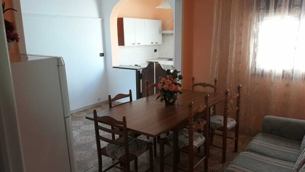 Un coin repas avec une table et des chaises en bois, un réfrigérateur et un canapé.