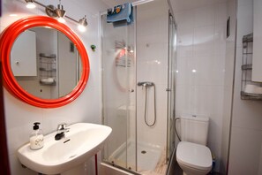 A modern bathroom with a glass-enclosed shower, a white sink, and a toilet.