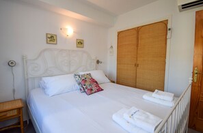 A bedroom with a bed, pillows, a wooden wardrobe, a bedside table, and a wall-mounted light. - Ref: 254 Apartment with pool and fantastic location in Los Boliches (Fuengirola)