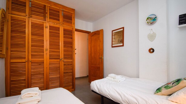 A bedroom with two beds, wooden wardrobes, and a door leading to another room.