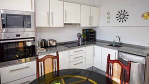 A modern kitchen with white cabinets, stainless steel appliances, a granite countertop, and a dining table with chairs.