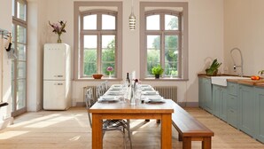 A kitchen with a wooden table set for dining, a white refrigerator, and blue cabinets. - Spacious and stylish in the monument to the Müritz, near the lake and golf course (Lexow)
