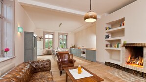 A spacious living room with a leather sofa, a wooden table, and a fireplace. - Spacious and stylish in the monument to the Müritz, near the lake and golf course (Lexow)