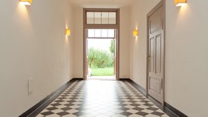 A hallway with a checkered floor, a door at the end, and wall-mounted lights. - Spacious and stylish in the monument to the Müritz, near the lake and golf course (Lexow)