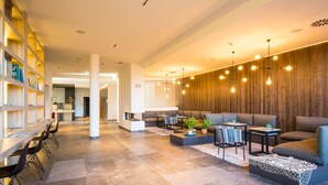 A spacious lobby with a long reception desk, seating area with sofas and tables, and a wooden accent wall. - Comfortable large suite, pool and sauna, 30 meters to the beach, large south-facing balcony (Börgerende)