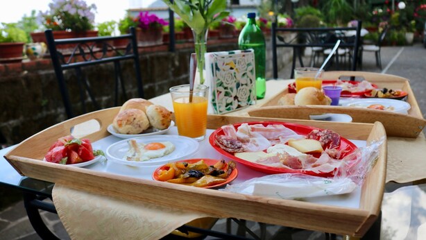A breakfast tray with various foods and drinks on an outdoor table.