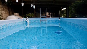 A swimming pool with a tiled floor, a ladder, and a floating ring.