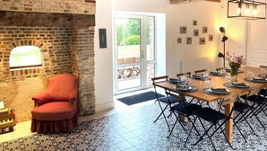 A dining area with a brick wall, a red chair, and a table set for four.