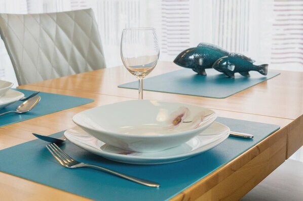 Una mesa de comedor con un tazón blanco, una copa de vino y un adorno con forma de pez.