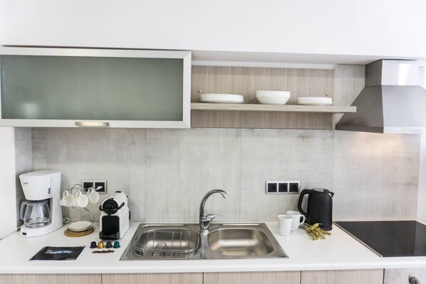 A modern kitchen with a built-in microwave, coffee maker, kettle, and a double sink.