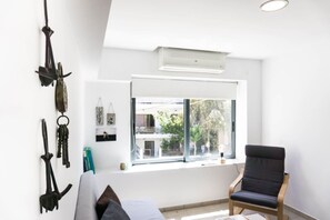 A room with a large window, a ceiling fan, and a black chair. - Reflection of neutral warm `Urban Cocoa`` (Rethymno)