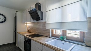 Moderni keittiö, jossa on sisäänrakennettu uuni, pesuallas ja ikkuna, josta on näkymä.