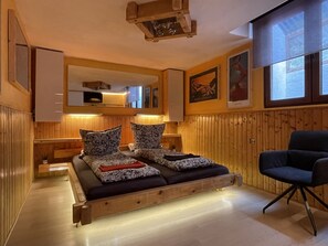 Un intérieur en bois comprenant un lit, une chaise et un miroir.