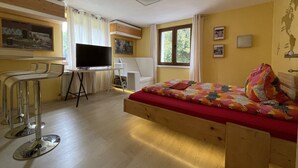 Una habitación con cama, escritorio, televisor y ventana.