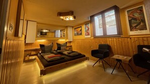 Una habitación acogedora con una cama, una silla y una mesita. Las paredes son de madera y hay una ventana con vistas.