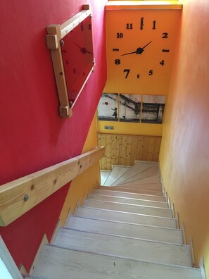 A staircase with wooden handrails and a red wall.