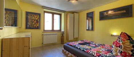 A bedroom with a bed, a wardrobe, a radiator, and a window.
