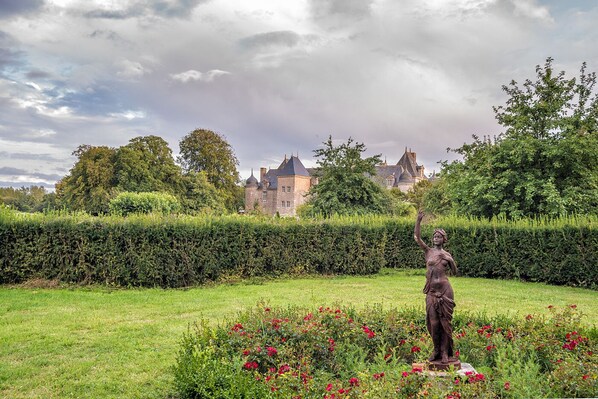 A statue in a garden with a castle in the background.