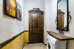 Comfortable room with a door, washing machine, and mirror, plus two framed artworks on the wall.