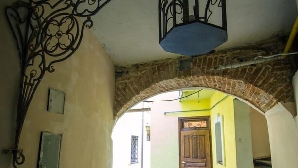 A narrow alleyway with a brick archway and a decorative metal fixture above. - Apart-Hotel Kraft (Lviv)