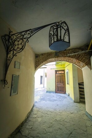 A narrow alleyway with a brick archway and a decorative metal fixture above. - Apart-Hotel Kraft (Lviv)