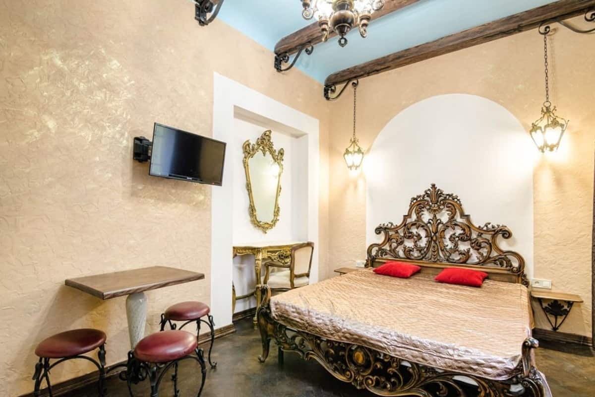 A bedroom with a bed, a desk, a chair, and a TV.