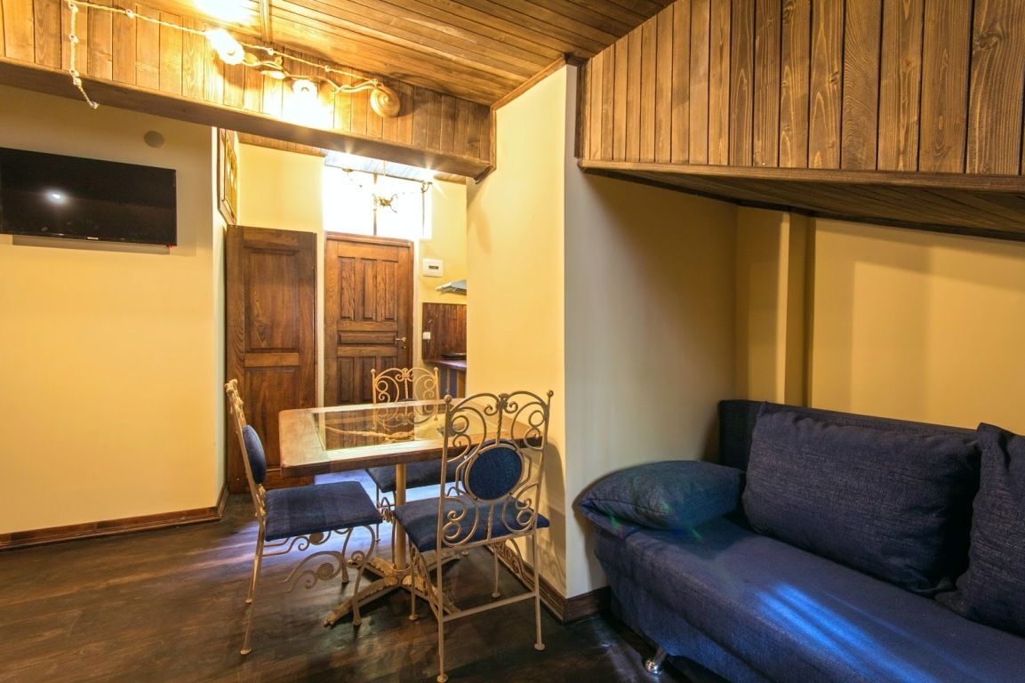 Een gezellige kamer met een houten plafond, een eettafel met stoelen en een bank.