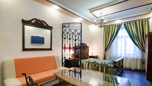 A room with a sofa, a glass-top table, a decorative partition, a bed, and a window with curtains. - Apart-Hotel Kraft (Lviv)