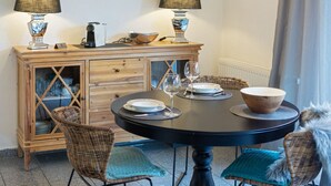 Een eetgedeelte met een ronde tafel, twee stoelen, een houten kast met glazen deuren en twee lampen.