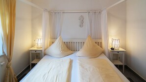 Een tweepersoonsbed met twee kussens, een nachtkastje met een lamp en een radiator boven het bed.