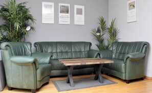 A green leather sofa with a wooden coffee table in a room with a grey floor and white walls. - Quiet location and yet right in the middle (Risum-Lindholm)