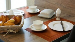 Een ontbijttafel met brood, een kop, een bord en een boterpot.