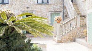 Un edificio de piedra con una escalera y una palmera grande al frente.