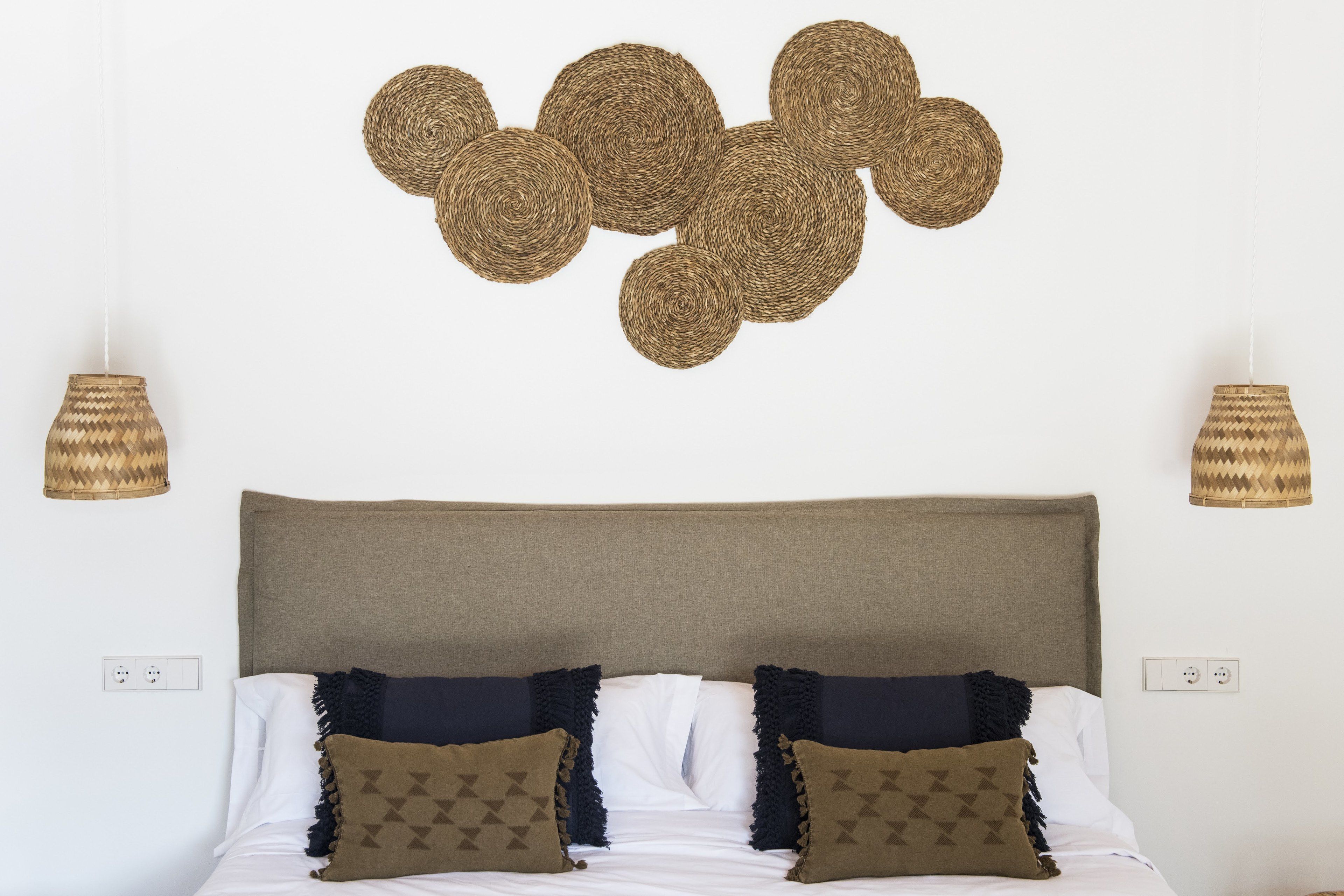 Una cama con cabecera, dos lámparas de pared y un adorno mural.