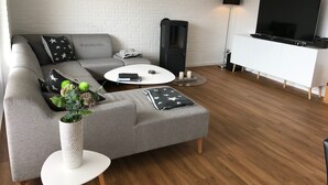 Una sala de estar moderna con un sofá gris, una mesa de centro blanca y un televisor de pantalla plana sobre un mueble blanco.