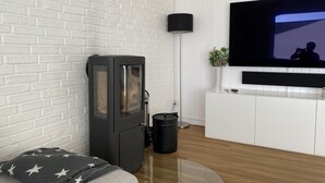 Una sala de estar moderna con una pared de ladrillo blanco, una chimenea negra, un mueble blanco y un televisor de pantalla plana montado en la pared.