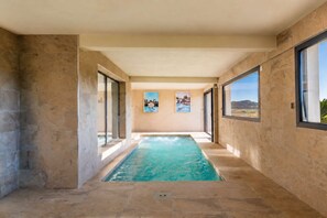 Une piscine offrant une vue sur le paysage grâce à de grandes fenêtres.