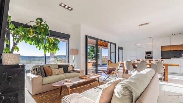 Un salon moderne comprenant un canapé, une table basse et un coin repas avec des chaises et une table.